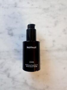 Nottnuit Radiance Face Serum i svart flaska på marmorbakgrund.