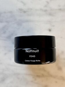 Nöttnuit FEND ansiktskräm i svart burk på marmorbakgrund.